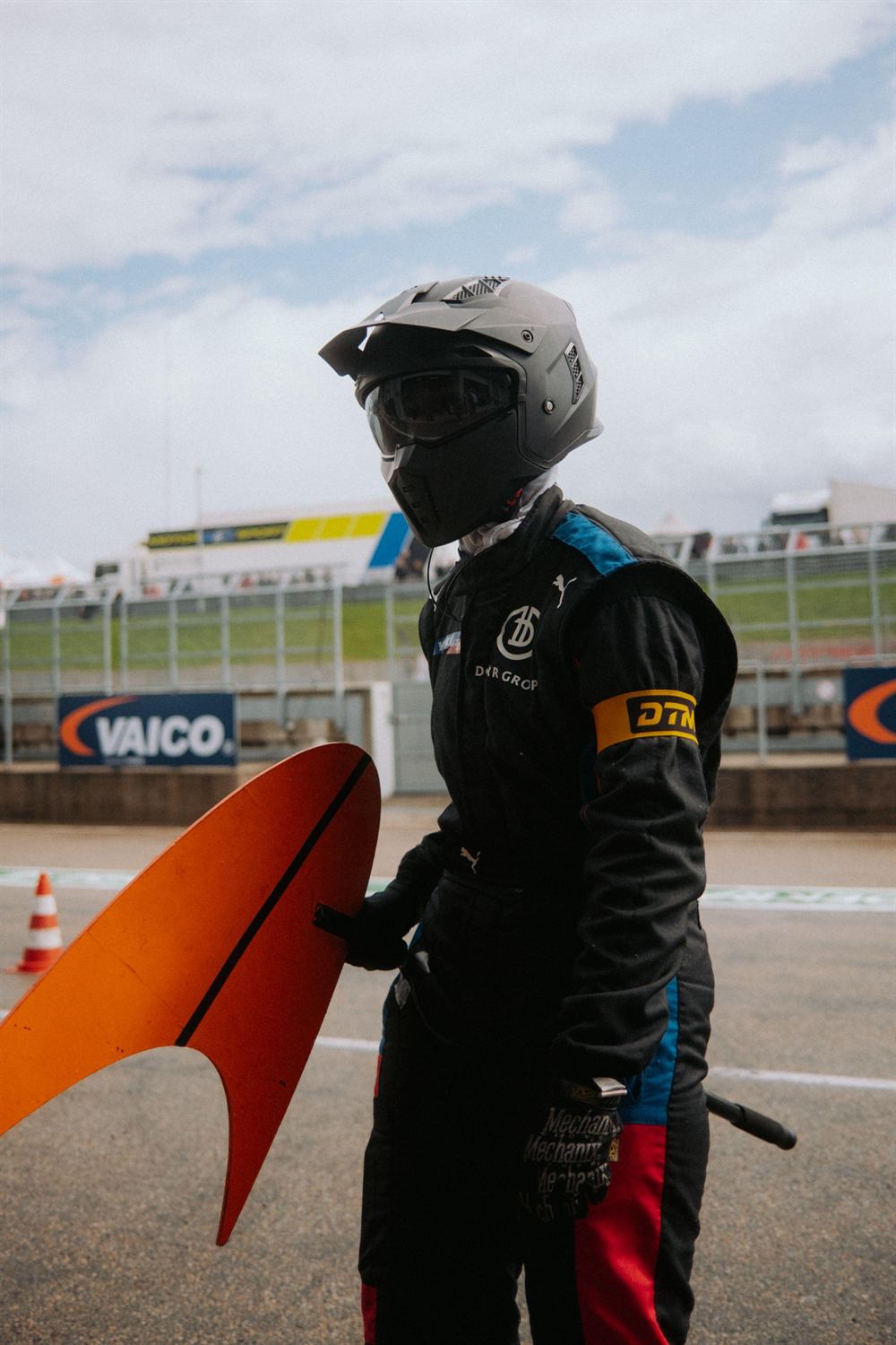 Mandy Paschen in racing gear with helmet next to the McLaren bodywork